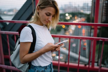 Genç kadın yolcunun rezervasyon yapmak sırt çantası ile smartphone köprüde, dalgın hippi kız CIT içinde yürümek telefon üzerinde navigasyon uygulamasındaki konumu arama gezinme sırasında kullanma online