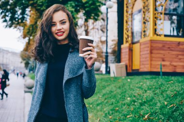 Yarım uzunluk portre mutlu çekici genç kadın moda rahat lezzetli kahve el açık havada promosyon arka plan reklam metin mesajınız için ayakta kılığına girmiş