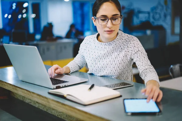 熟练的女设计师在眼镜安装应用在桌面上使用现代技术的触摸板工作 女实业家阅读收入信息从空白平板显示器坐在办公室 — 图库照片