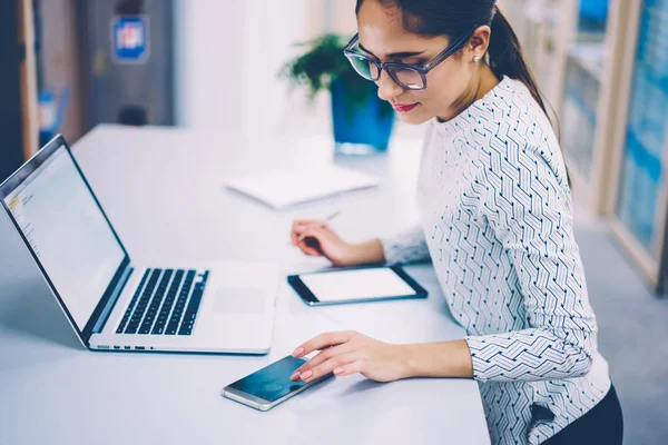 Brunetka Podnikatelka Pracující Kanceláři Kontrola Upozornění Smartphone Synchronizace Souborů Netbook — Stock fotografie