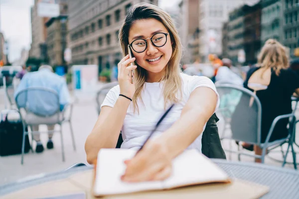 幸せな若いアジア女性割引について情報お問い合わせサービス演算子を書く眼鏡で陽気な女の子携帯情報中に友達計画プロジェクトと話しながら日記で指摘 — ストック写真