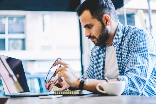 Erkek grafik tasarımcısı kullanarak uygulama iş dizüstü bilgisayarda çevrimiçi dosya indirme ağlarından office coworking oturan netbook okuyan adam serbest üzerinde çalışma için konsantre