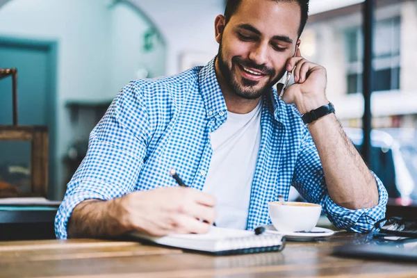 Homem Sorridente Falando Celular Escrevendo Informações Notebook Durante Coffee Break — Fotografia de Stock