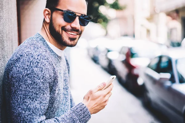 サングラス アウトドア携帯電話を介してテキスト メッセージを送信するレジャーを楽しむ都市通り 幸せな男に時間を費やしている間ソーシャル ネットワークでチャット用のスマート フォンを使用して肯定的な流行に敏感な男 — ストック写真