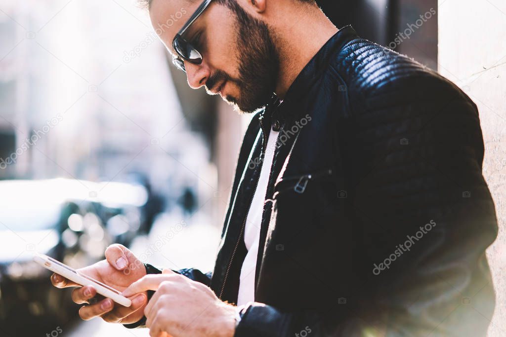 Cropped image on concentrated male person using application on cellular for online banking standing on street,hipster guy reading notification on smartphone sending multimedia messages outdoors