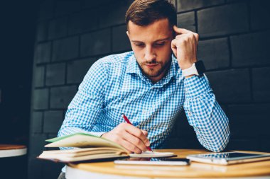 Akıllı erkek öğrenci ders notlar proje ile sorunları çözme accountings yapma kafe iç, dalgın işadamı otururken yazma fikirleri Not Defteri'nde planlama konsantre