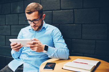 Gözlük online araştırma taşınabilir pc, Finansal Haberler tarama web sayfasında kafede dijital tablet okuma ciddi iş adamı kullanarak proje stratejisi planlama iç yapım genç erkek öğrenci