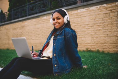 Açık havada istimal laptop için araştırma ödevi gülümseyen afro Amerikan öğrenci portresi. Hippi kız sınavları açık havada için hazırlanıyor Üniversitesi kampus içinde styling olumlu koyu derili