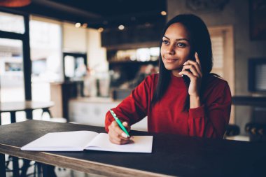Bilgi hizmeti işleci ile cep telefonuna konuşurken dikkat çeken çekici afro Amerikan Yöneticisi. İş kadını cep not defterinde yazılı proje planlama hakkında konuşmayı koyu derili
