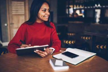 Gülümseyen afro Amerikalı kadın mimar serbest zaman sırasında yeni proje için kroki çizim iş ile memnun. Güzel genç tasarımcı öğrenci ödev görev kafede yaparken grafik oluşturma