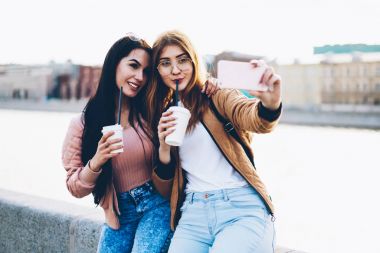 Arkadaşlar turist şehir arka plan üzerinde gezisi sırasında fotoğrafları yapma elinde sokak kahve ile en iyi. Birlikte kentsel belirleyen ve Smartphone'da selfie fotoğraf çekmek dinlenme olumlu hipster kızlar
