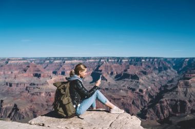 Milli Park, dağ tepe üzerinde yürüyüş sırasında hücresel dinlenme üstünde posta kontrol kadın turist Yolculuk tutkusu kayalık uçurum üzerinden ileti göndermek için mobil bağlantı kullanarak sırt çantası ile gülümseyen kız
