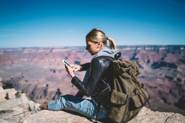 Genç kadın turist mobil veri ağı telefonla mesaj gönderme dağlarda memnun cliff, hippi kız Yolculuk tutkusu için Smartphone uygulama kullanarak üzerinde dinlenme gidin yürüyüş sırasında