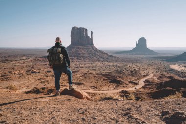 Erkek Gezgin Monument valley, hipster adamla kuru çöl kumtaşı oluşumları ile hiking güneybatı ABD keşfetmek sırt çantası, doğal çevrenin güzel sahne zevk arkadan görünüm