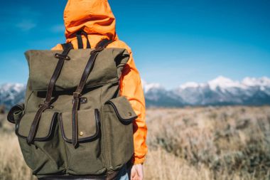 Hiking, yolculuk sırasında doğa Peyzaj ve çevre keşfetmek genç hipster backpacker karla kaplı tepeler, güzel sahne bakmak sırt çantası ile arkadan görünüşü kadın turist turuncu ceketli 