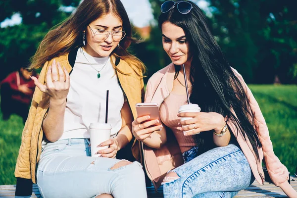 Esmer blogger posta lezzetli kahve zevk bankta oturan modern telefon aygıtı üzerinde en iyi arkadaşı için Internet Web sitesinde gösterilen. Hippi kız giyim fotoğraflarını smartphone açık havada üzerinde tartışıyor