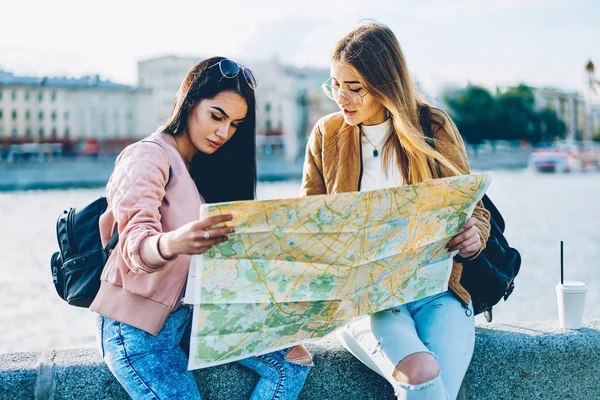 最好的朋友游客在太阳镜看地图和寻找正确的方向 他们的旅行在新城 两位时髦女孩讨论未来在城市环境中坐在户外旅行的路线 — 图库照片