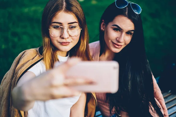 漂亮的时髦女孩看着现代智能手机的前摄像头 并制作自拍照片上传在社交网络和得到许多喜欢的朋友 在蜂窝上拍照的年轻女性 — 图库照片