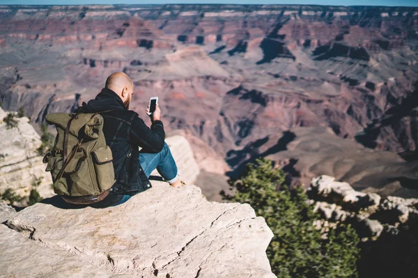 Hipster Cara Com Mochila Sentado Alta Montanha Penhasco Usando Smartphone — Fotografia de Stock