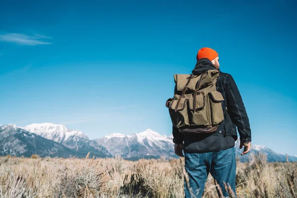 后面的男性旅行者与背包有徒步旅行 Tor 探索野生环境和景观 时髦的家伙步行到达目的地在山区徒步旅行期间在美国 — 图库照片