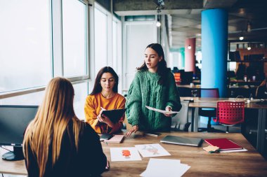 Profesyonel kadın tasarımcılar kendi moda iş brifing sırasında geliştirmek için yaratıcı fikirler tartışıyor. Üç arhitects proje üzerinde işbirliği içinde ofis iç oturma vasıl okul sırası ile skeçler