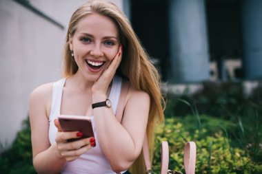 Sersemlemiş hippi kızın yarım boy portresi kameraya gülümseyen ve ruh haliyle ilgili duygularını ifade eden şehir sokaklarında mutlu bir kadın modern dijital akıllı telefonu telefonla telefonla arıyor.