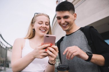 Akıllı teknolojinin neşeli erkek ve kadın kullanıcıları cep telefonu güncellemesinden memnun olan mutlu erkek ve kadın cep telefonu güncellemesi hakkında iyi haberler içeren makaleleri kontrol ediyorlar.