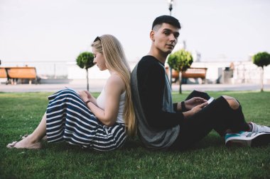 Elinde cep telefonu olan yakışıklı hipster adamın portresi kameraya bakarken kız arkadaşının yanında olması ve onunla canlı iletişimi görmezden gelmesi web sitesindeki takipçilerle sohbet etmeyi tercih etmesi.