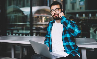 Sakallı kazak hippi adam dışarıda kafede dinleniyor ve akıllı telefonla konuşuyor. Arkadaşı dizüstü bilgisayarında oturuyor. Yakışıklı genç serbest çalışan adam uzaktan kumanda sırasında cep telefonundan arıyor.