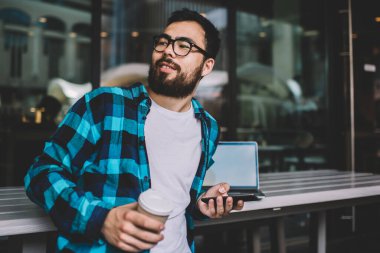 Asyalı, sakallı hippi, şehir merkezlerinde kahve molası veriyor. İnternette sohbet etmek için cep telefonu kullanıyor. Elinde akıllı telefonu olan yakışıklı bir blog yazarı var.