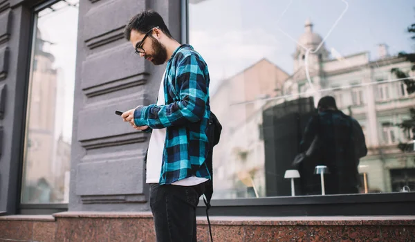 スマートフォンでアプリケーションを使用してメールをチェックしながら 街の通りに時間を過ごすハンサムな男 流行の服の男性は屋外のソーシャルネットワークで携帯電話チャットを介してテキストメッセージを送信します — ストック写真