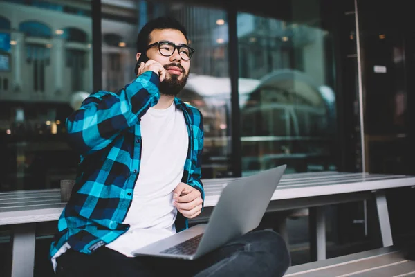 Freelancer Masculino Asiático Chamando Smartphone Enquanto Senta Com Computador Portátil — Fotografia de Stock