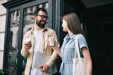 Kafeterya yakınlarındaki kahve molası sırasında eğlenmekten bahseden neşeli çok kültürlü arkadaşlar, şehir merkezindeki tanıtım alanında canlı iletişimden keyif alan mutlu erkek ve kadın, ilişki kavramı.