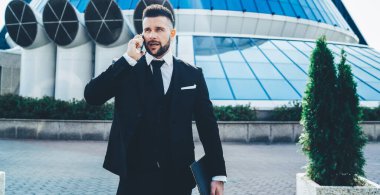 Ciddi meşgul erkek yöneticiler, internet üzerinden otel rezervasyonu için rezervasyon doğruladı. Yurt dışında konaklama ayarlamak için telefon görüşmesi, işletme sahibi iletişimi