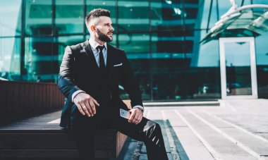 Düşünceli erkek şirket çalışanı şehir ortamında oturuyor ve düşünceli bakışlarla yeni bir projeye başlamak için yöneticileri düşünüyor. Finans bölgesinde dalgın bir iş adamı.
