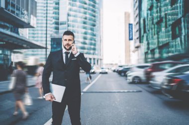 Finans bölgesinde dizüstü bilgisayarı olan yakışıklı erkek girişimcinin yarı boy portresi ve işletme müşteri hizmetleri ile uluslararası sohbet yapıyor.