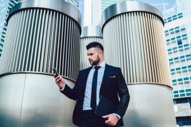 Şaşkın iş adamının cep telefonu aygıtıyla cep telefonundan gelen mesajları kontrol etmesinin altında, profesyonel para web sitesinde kafası karışmış erkek finans uzmanı haberleri okuyor