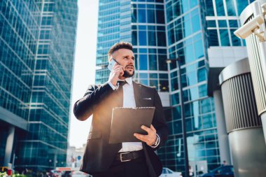 Megalopolis caddesinde muhasebe sırasında cep telefonu cihazını online danışmanlık için kullanan kafası karışmış erkek ekonomistin altında akıllı bir adam uygulamayla uluslararası cep telefonu sohbeti yapıyor.