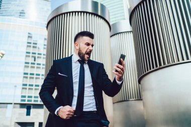 Manyak erkek girişimci, Megalopolis 'in finans bölgesindeki akıllı telefon cihazına bağırarak işletme sorunlarını çözmede sorun yaşıyor, mutsuz bir adam mobil gadge' a bağırıyor.