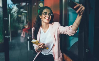 Görsel gözlüklü neşeli kadın kameraya gülümseyen ve özçekim resimlerine tıklayarak sosyal web sitesindeki takipçileri cezbetmek için göz korumasını sağlıyor. İnternet bağlantısının keyfini çıkarıyorlar.