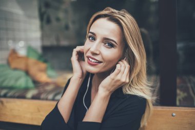 Giyilebilir elektronik kulaklıklı çekici bir kadın melodinin portresi. Çalma listesindeki favori müziği dinliyor ve boş zamanlarında kameraya bakıyor. Güzel bir kadın müzik kaydından zevk alıyor.