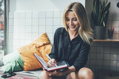 Başarılı kadın, kafede otururken üretken bir gün geçirdiği için mutlu kadın zaman yönetimi kontrol listesi yazıyor, pozitif öğrenci kapalı alanda eğitim alırken ders kitabına not alıyor.