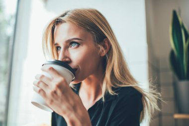 Düşünceli hippi kız, sarı saçlı, düşünceli, düşünceli. Yemek fincanından lezzetli kafein içen, kahve içen, elinde kahve tutan ve tadını çıkartan çekici kadın.