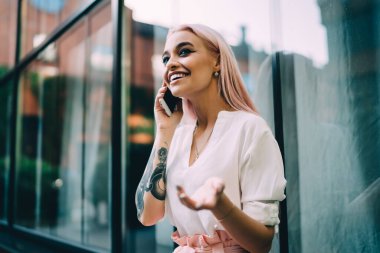 Neşeli bir kadın milenyumu, elinde büyük bir dövmeyle en iyi arkadaşına telefon ediyor, cep telefonunda gezinen bağlantıyı kullanıyor, neşeli bir hippi kız gülümsüyor ve telefonla konuşuyor.