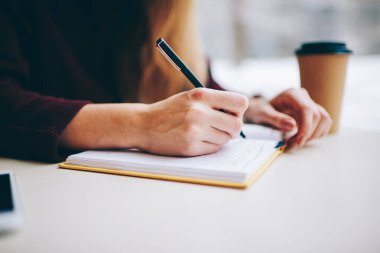 Seçici odaklanma kapalı eğitim için ders kitabına bilgi yazmak kaliteli siyah kalem kullanarak, Kafeterya masasında oturan kadın görüntüsü kafeterya not defteri ile