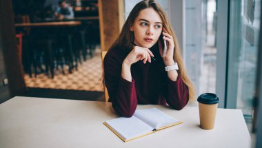 Milenyum bayan öğrencisi danışmanlık için müşteri hizmetlerini arıyor ve ders kitabına ana tezi yazıyor. Beyaz kadın operatörle cep telefonu konuşmaları yoluyla hesap bakiyesini kontrol ediyor.