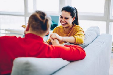 Neşeli, beyaz bir kadın kocasına gülümsüyor. Kanepede birlikte oturuyor, iletişim kuruyor, romantik bir çift birlikte eğleniyor. Evde eğleniyor, sohbet ediyor ve şakalaşıyor.