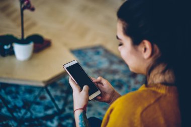 Modern akıllı telefona seçici bir şekilde odaklan ve ekranda bir kadının kısa mesaj göndermesini taklit et, hipster bir kızın evdeki kablosuz interneti kullanarak sohbet için cep telefonuna uygulama yüklemesini engelle.