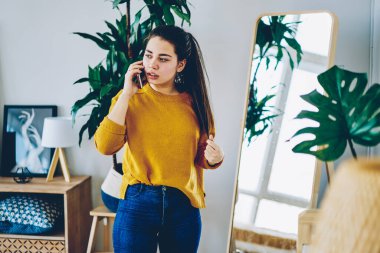 Gündelik giyinmiş düşünceli beyaz bir kadın cep telefonuyla arkadaşıyla konuşuyor. Aynanın yanında yeni bir kazak giyiyor. Düşünceli bir hippi kız telefon görüşmesi yapıyor.