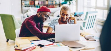 Özel ders sırasında tasarım yaptığı için kadın öğrenci başvurusunu dizüstü bilgisayarında gösteren yetenekli bir erkek öğretmen. Dizüstü bilgisayarın yanında alışveriş için internet sitesi olan genç bir evlilik.